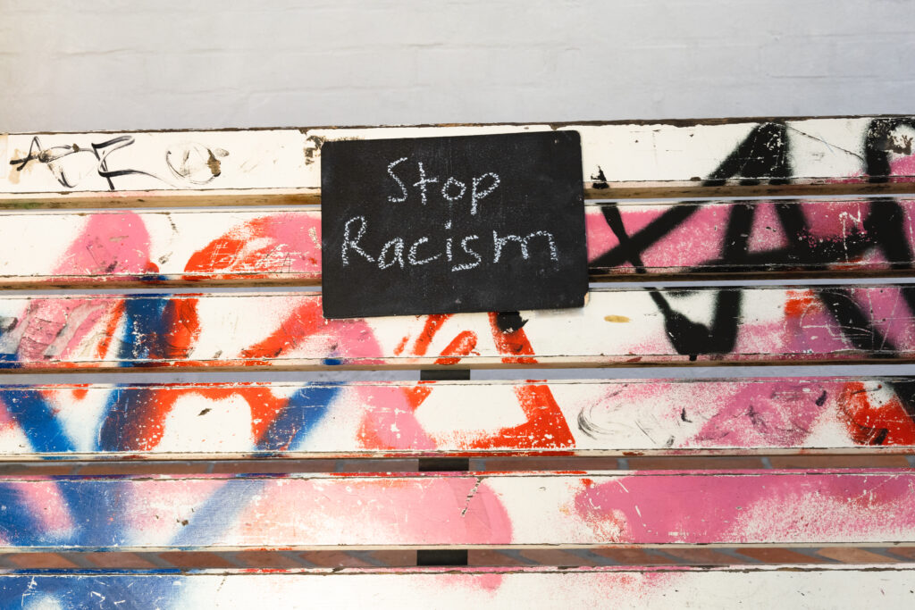 Schild mit der Aufschrift "Stop Racism" auf dem Parkbank-Exponat im Themenraum "Parkcafe"