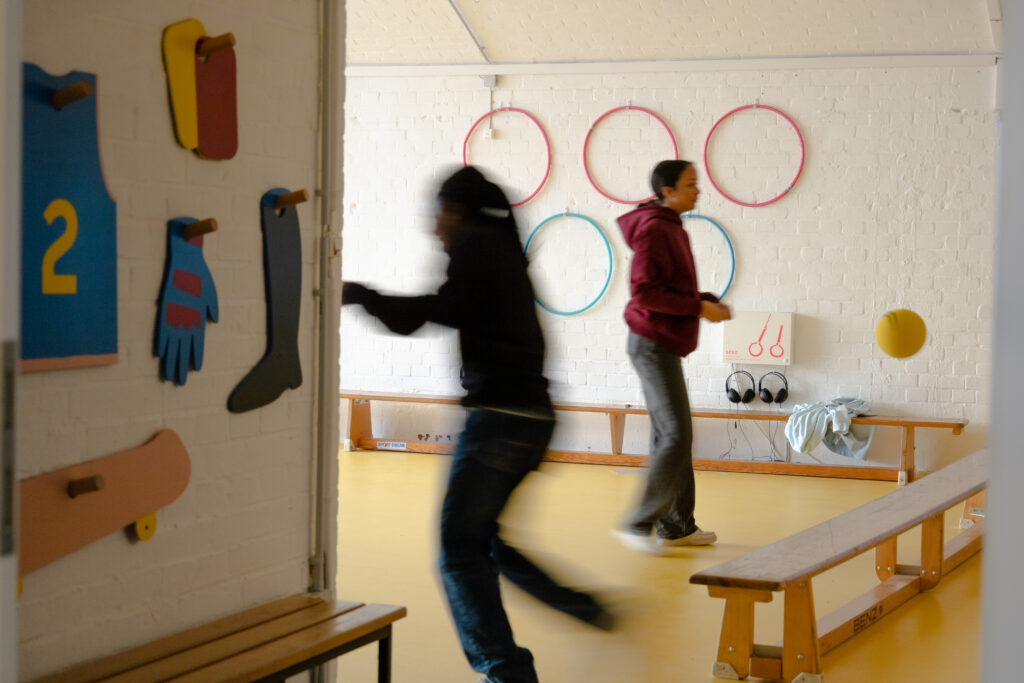 Zwei Schüler*innen toben in Themenraum "Sport", Bewegung und Spiel zwischen den einzelnen, vertiefenden Modulen